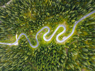 Beautiful mountain road in the forests of the Dolomites, Italy. Winding road in the Giau pass. Passo Giau serpentine. Famous road with many curves in the Dolomites mountains. Top view. Drone shot.