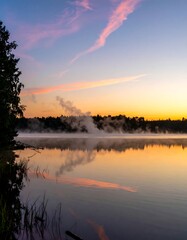 Obraz premium Misty sunrise over a calm lake, trees on shore
