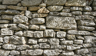 A detailed close-up view of a rustic stone wall in France, showing the textures and patterns of the stacked rocks
