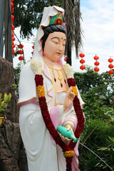 Guan Yin statue pouring amrita from vase, close-up detail at Buddhist temple in Kuala Lumpur, Malaysia &mdash; concept of compassion and spiritual blessing.