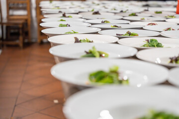 Many white plates prepared for a catering event