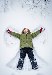 Playful Boy Playing in Snow in Winter Field - Making Snow Angels