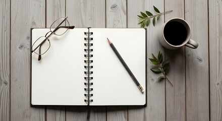 A cozy workspace featuring an open notebook, pencil, glasses, coffee mug, and green leaves on a wooden table