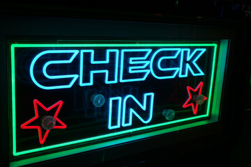 Vibrantly lit neon "CHECK IN" sign with red stars and green border at the bustling Goose Fair, Nottingham, England.