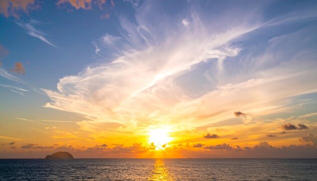 Vivid sunset over ocean horizon with bright sun. Streaks of clouds and a small island complete the scenic view. Calm water reflects the colourful sky