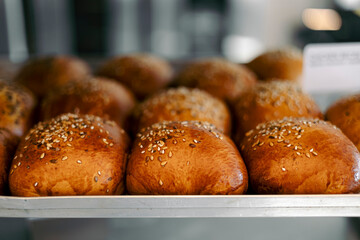 Freshly baked buns decorated with sesame seeds in a bakery for sale.