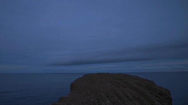 Serene Coastal Scene at Dusk with a Dramatic Sky and Calm Sea Horizon, Evoking Tranquility and Nature's Beauty in Diminishing Light