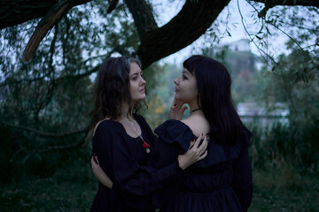 two women in the black long dresses on Halloween, brides of Dracula, vampires, bite, kiss,