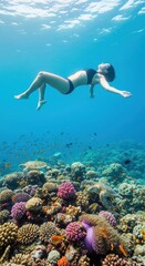 Woman floating gracefully above vibrant coral reef in clear blue ocean