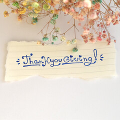 Thanksgiving Text on Torn Paper with Leaves. Rustic torn paper with handwritten “Thanksgiving” lettering, framed by colorful autumn leaves.