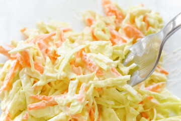 Coleslaw salad with carrot and cabbage on fork.
