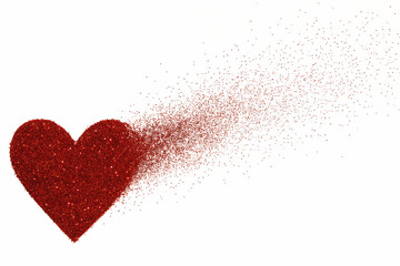 Red heart shape dissolving into a cloud of red glitter particles sparkle isolated on a transparent background