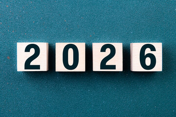 2026 Happy New Year. Wooden cube block 2026 greeting card on green. Concept 2026 New Year background. Business, resolutions, goals, inspiration, success, ideas