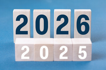 2026 Happy New Year. Wooden cube block change from 2025 to 2026 on blue. Concept 2026 New Year background. Business, resolutions, goals, inspiration, success, ideas