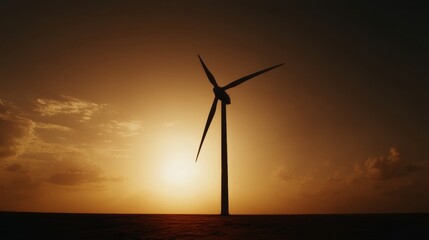 Silhouette of a wind turbine against a sunset backdrop with expansive open fields stretching to the horizon where the su