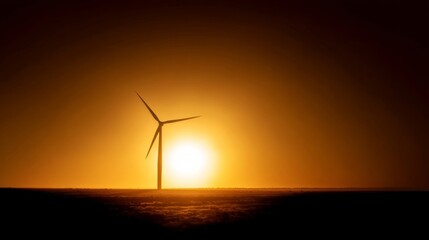 Wind turbines stand tall against a vibrant sunset sky with warm yellow to deep brown gradients,