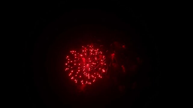 Colorful fireworks explode in the night sky over a riverside festival.