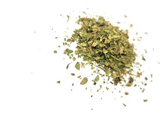 Dried pieces of parsley leaves against a white background