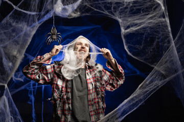 Creepy scary zombie man with ugly makeup trapped in cobweb on spooky spider web background....