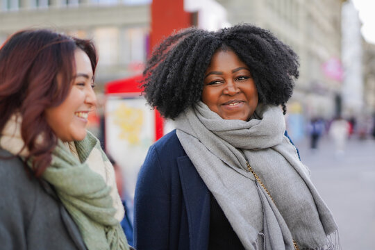 Multiracial millennial generation women having fun waiting together at bus station in the city - Diversity, friendship and winter concept - Powered by Adobe