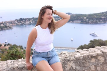 Beautiful woman sitting on bridge in city