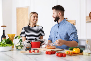 Happy couple cooking together at table in kitchen