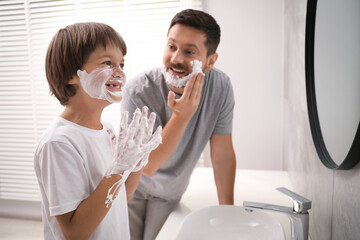 Father and son applying shaving foam on their faces in bathroom