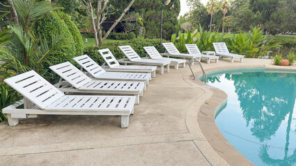White sun loungers lined beside relaxing swimming pool