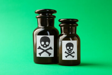 Bottles of poison with warning signs on green background, closeup