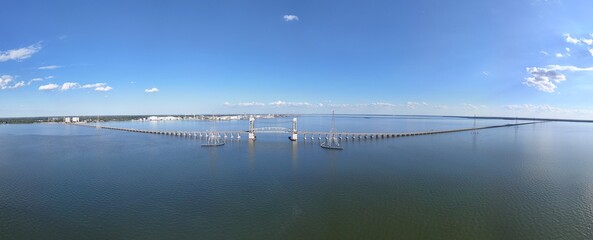 James River Lift Bridge JRB spans a calm waterway, supported by tall towers . This infrastructure connects distant shores, reflecting on blue water beneath a bright, clear sky