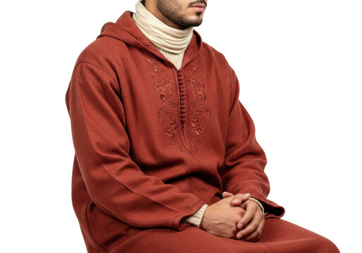 Isolated man in traditional robe sitting down wearing cream-colored turtleneck and hood