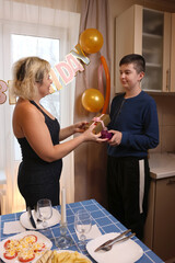 A boy gives his aunt a gift, wishing her a happy birthday.