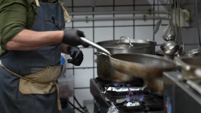 Professional chef cooking and tossing pasta in a frying pan