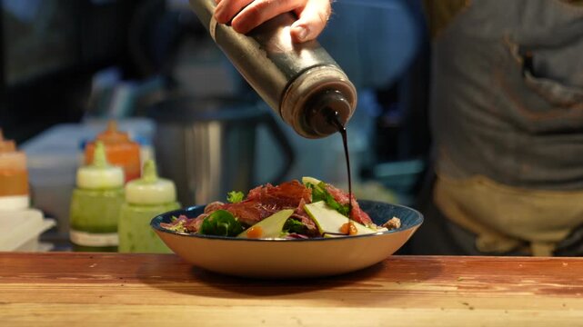 Professional chef garnishing delicious meat and pear salad