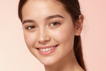 Obraz premium close-up portrait of a young girl with natural makeup smiling against a soft pink background highlighting healthy skin and beauty for cosmetic advertising