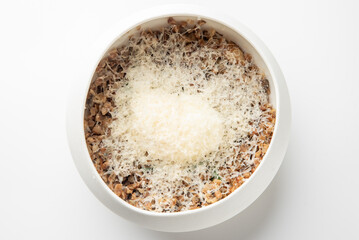 White bowl with cooked minced food topped with finely grated cheese, isolated on white background. Simple rustic presentation ideal for culinary, recipe, or food styling themes