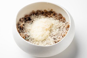 White bowl with cooked minced food topped with finely grated cheese, isolated on white background. Simple rustic presentation ideal for culinary, recipe, or food styling themes