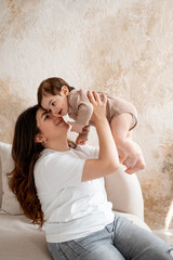 baby and mother, mom hugging baby at home, maternal love and care, mom with a small child, brown or beige background