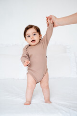 the baby learns to walk by taking the first steps, the mother holds the hand of a small child teaching him to walk