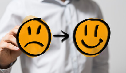 Stock photo depicting a hand drawing emoticons, showing a transition from sadness to happiness....