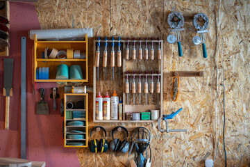 Carpenter workspace with neatly arranged hand and power tools mounted on panel in storage unit. Professional wood shop, tool organize on pegboard, efficient workshop layout, precise instrument storage