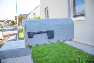 metal mailbox mounted on a post in front of a residential house