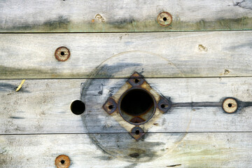Textured Wooden Surface with Holes and Rusty Fixtures Close-Up
