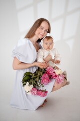 mom with a baby little daughter with peony flowers on a white isolated background, space and room for text