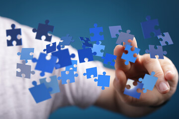 Hand interacting with floating puzzle pieces.  Concepts: solution, strategy, teamwork, success, connection.