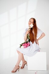 a young beautiful girl with peony flowers on a white isolated background, space and room for text