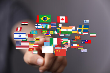 A person's hand is touching a collection of flags, symbolizing globalization, international...