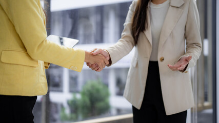 Fototapeta premium Asian businesswomen professionals shake hands close deal partnership agreement modern office collaboration trust successful meeting