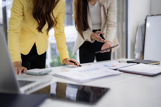 Asian businesswomen analyzing financial reports discussing strategies office professionals collaborate on data planning new project ideas - Powered by Adobe
