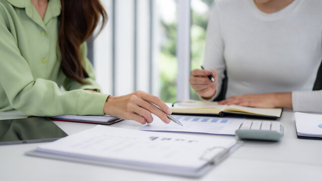 Professional business women collaborate analyze financial reports discuss growth strategy meeting room office setting